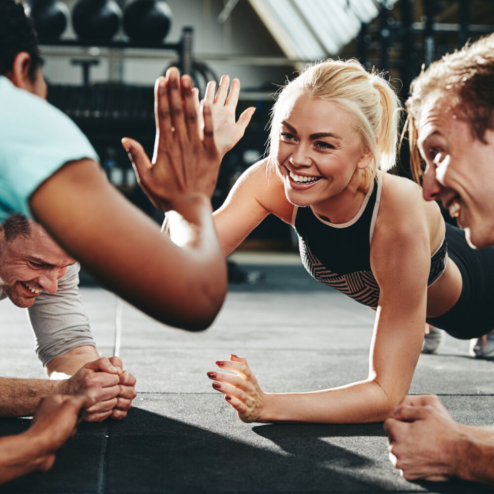 Two,Young,Women,In,Sportswear,High,Fiving,Together,While,Planking