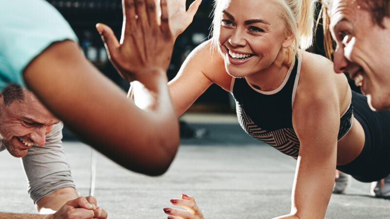 Two,Young,Women,In,Sportswear,High,Fiving,Together,While,Planking